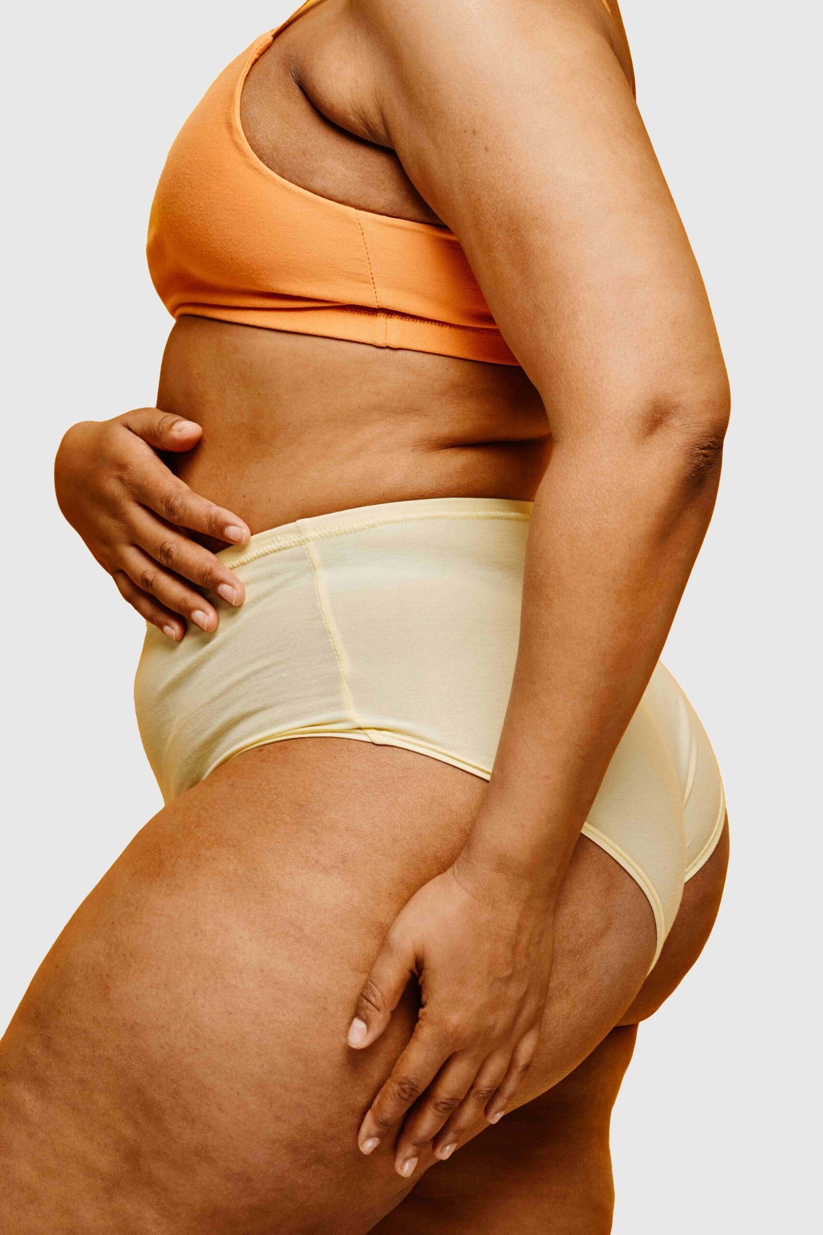 vertical-side-view-portrait-of-real-black-woman-wearing-underwear-against-vibrant-yellow-background copie (1)